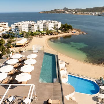 a pool and beach with buildings and water in the background