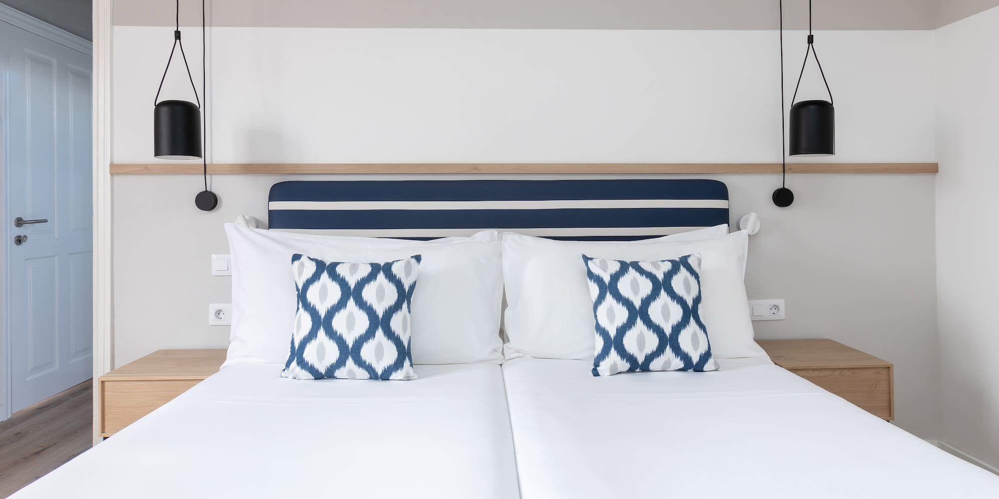 a bed with white sheets and blue and white pillows