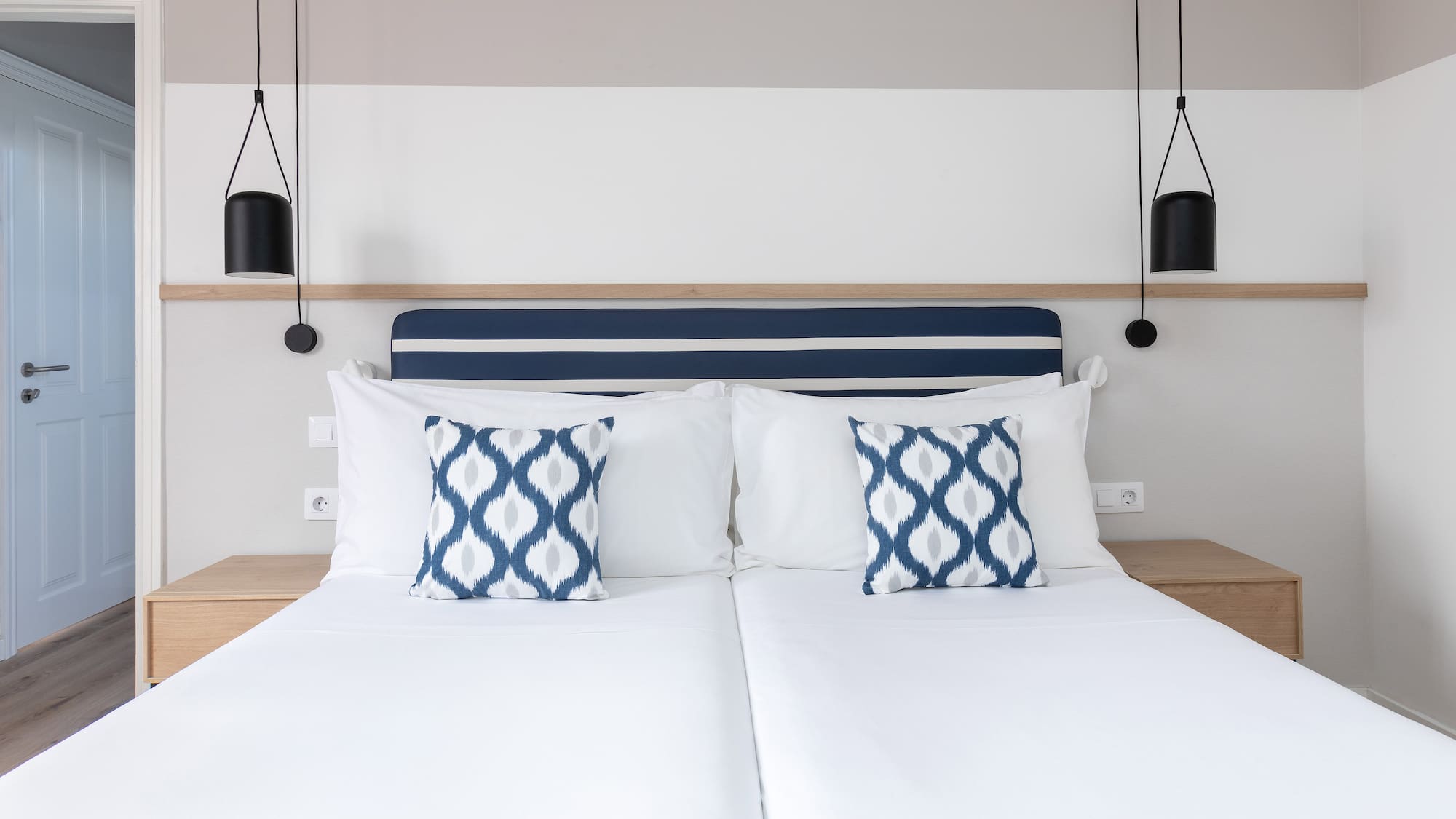 a bed with white sheets and blue and white pillows