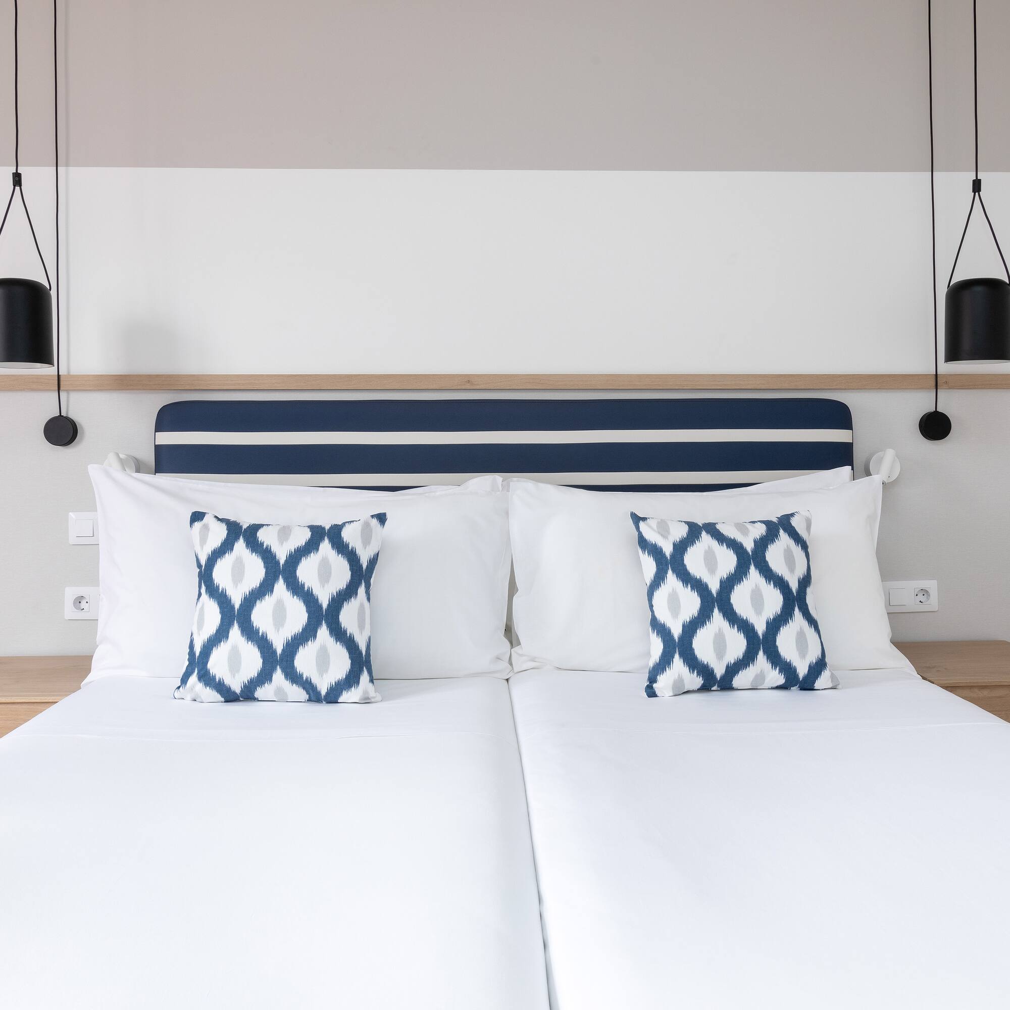 a bed with white sheets and blue and white pillows
