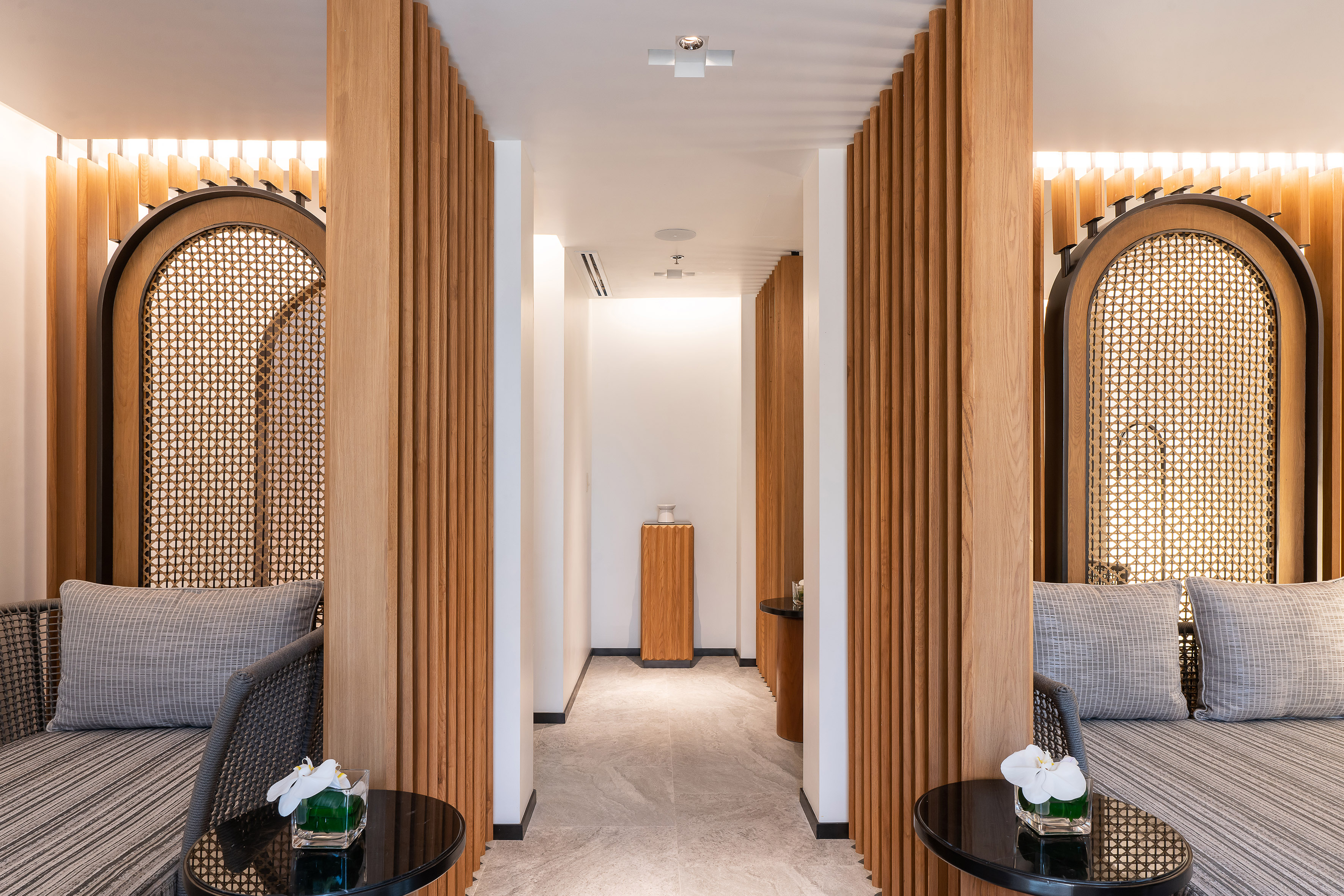 Modern spa lounge with wood slats, cane screens, and comfortable seating.