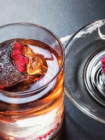 a glass of liquid with a spoon and a spoon on a plate