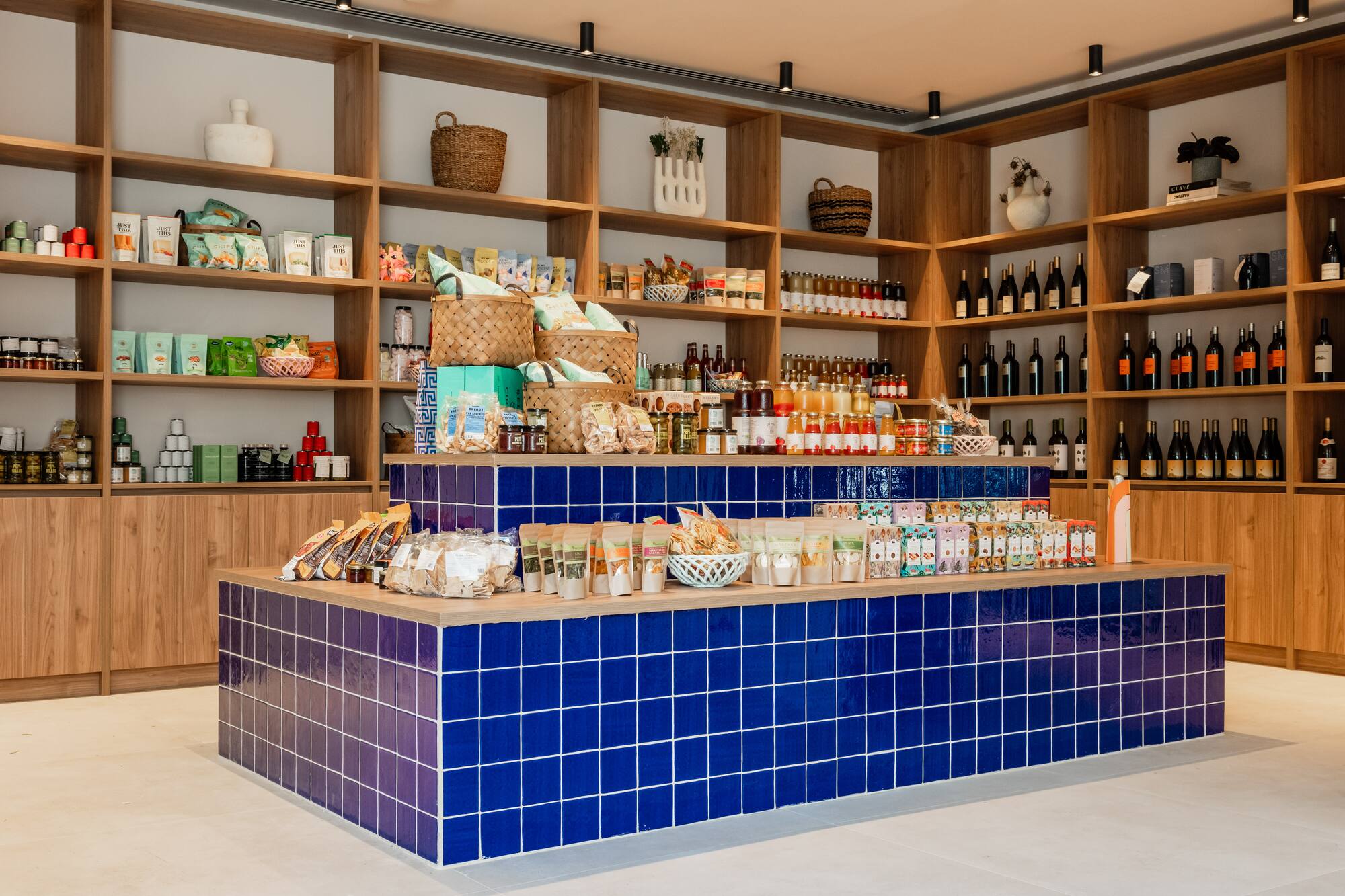 Gourmet food store with wooden shelves, wine, and blue tiled product display.
