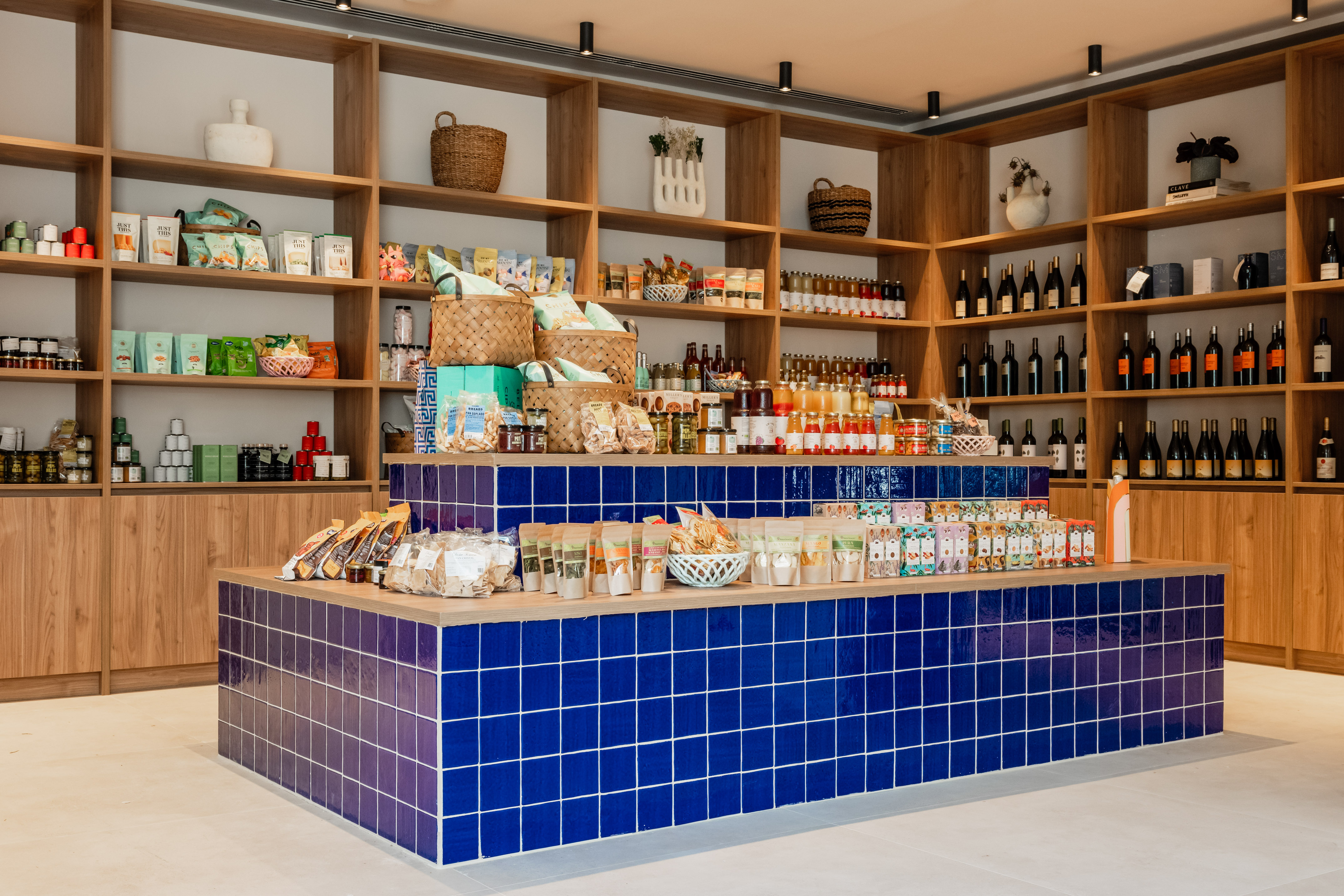 Gourmet food store with wooden shelves, wine, and blue tiled product display.