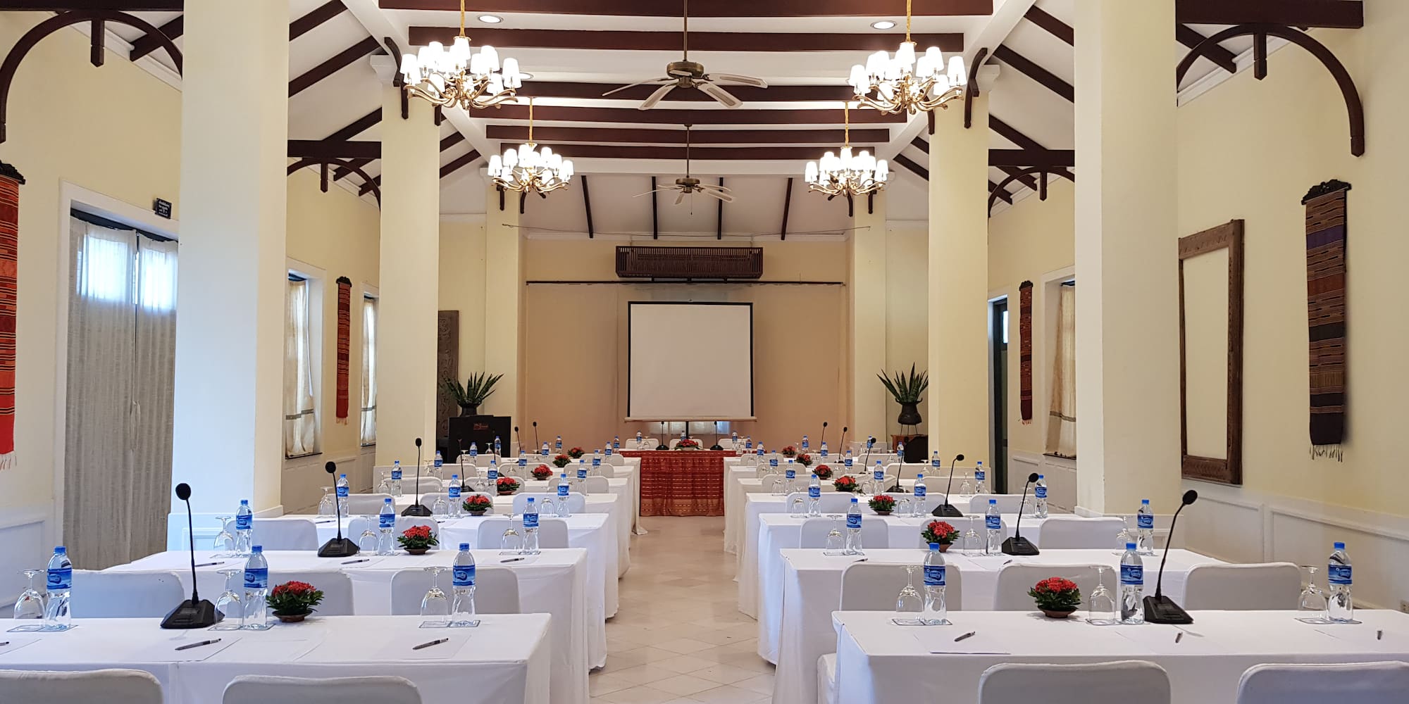 a room with tables and chairs and a projector screen