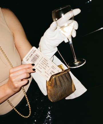 a woman holding a wine glass and a ticket