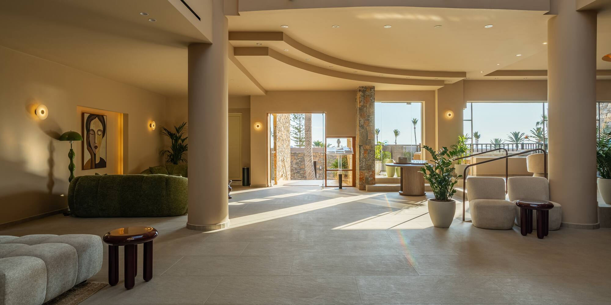 Elegant resort lobby with warm natural light, modern seating, and palm tree views.