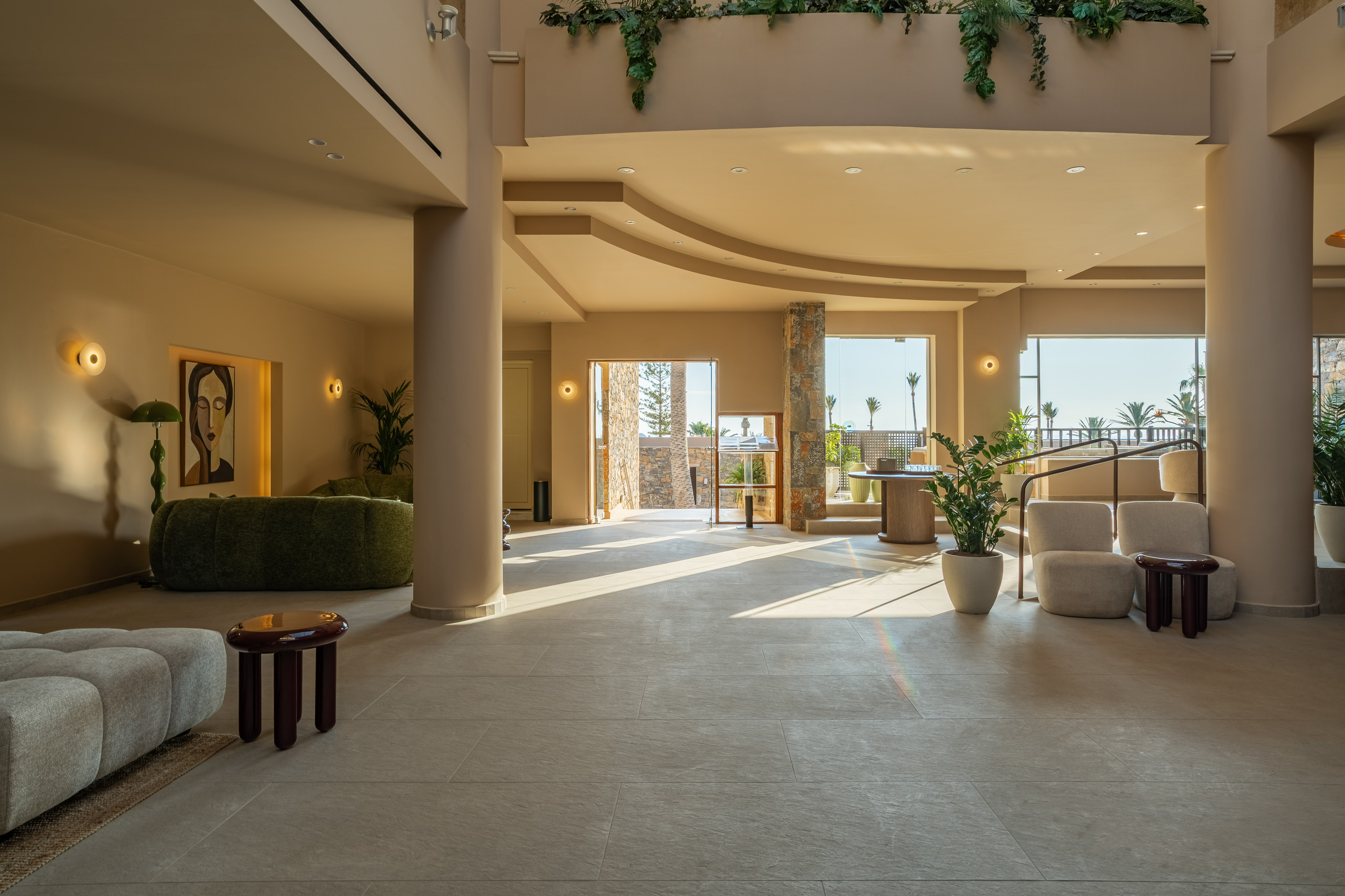 Elegant resort lobby with warm natural light, modern seating, and palm tree views.
