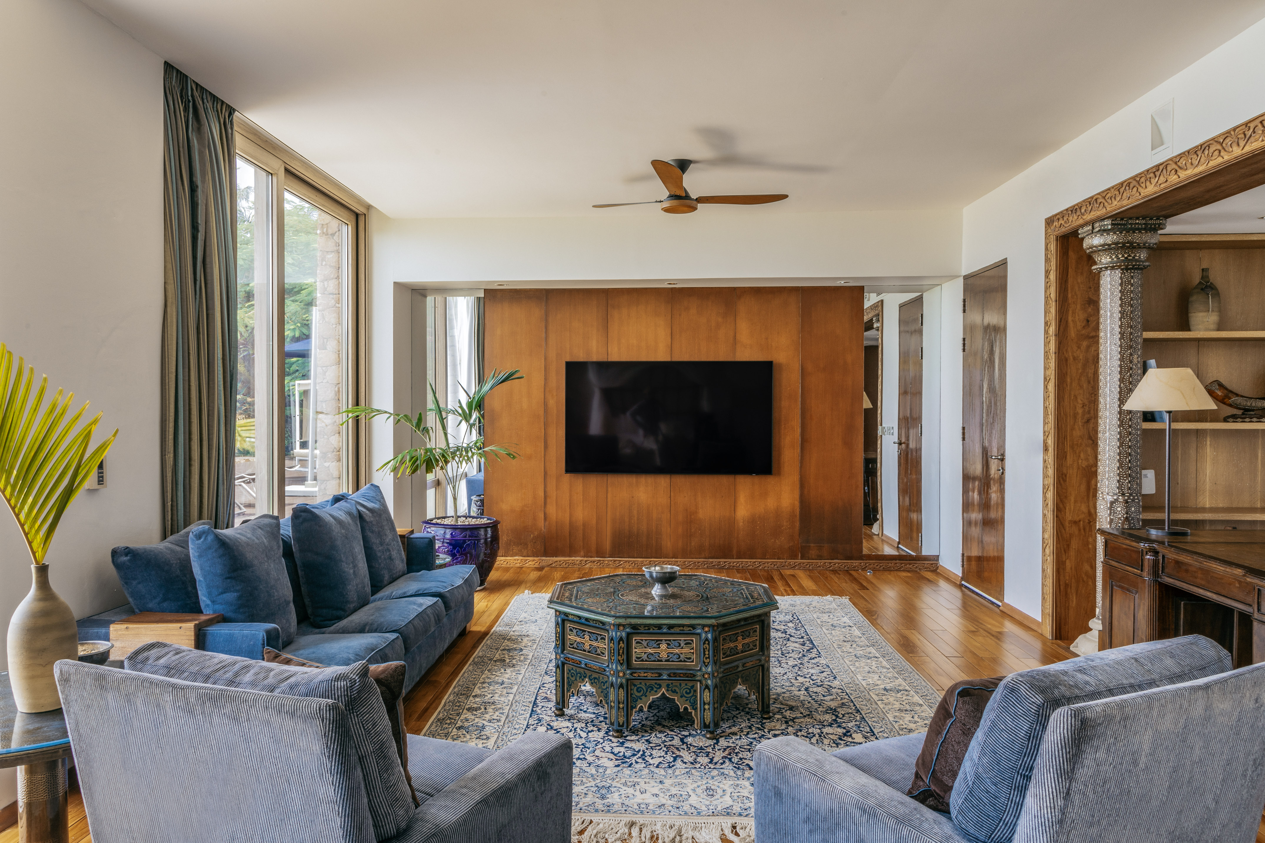 Blue sofa living room with ornate coffee table, wood paneling, and TV.