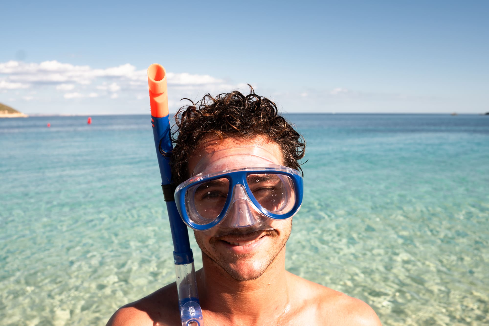Hombre con máscara de snorkel en aguas turquesas.