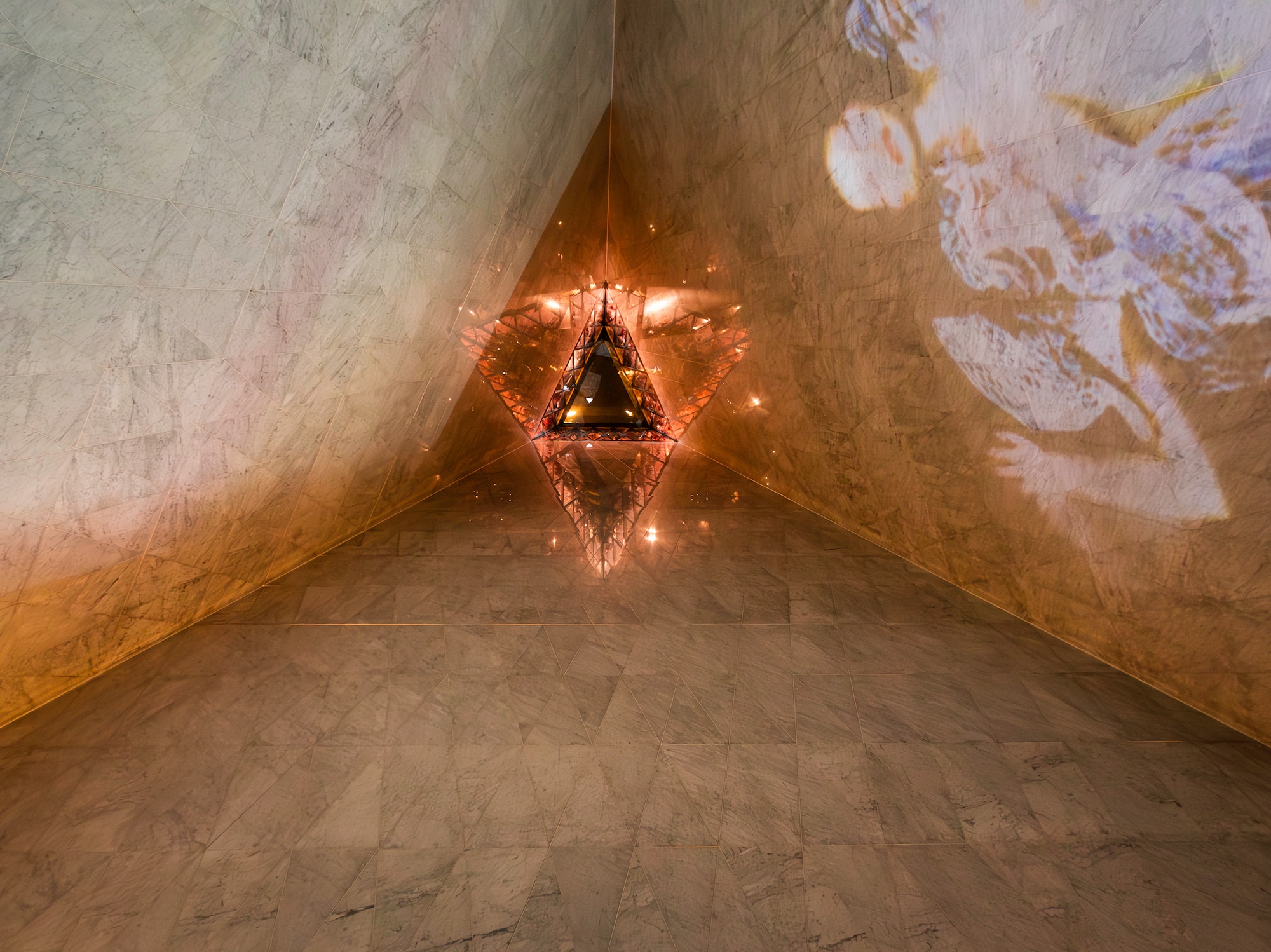 Glowing triangular light in marble corner with abstract projected art.