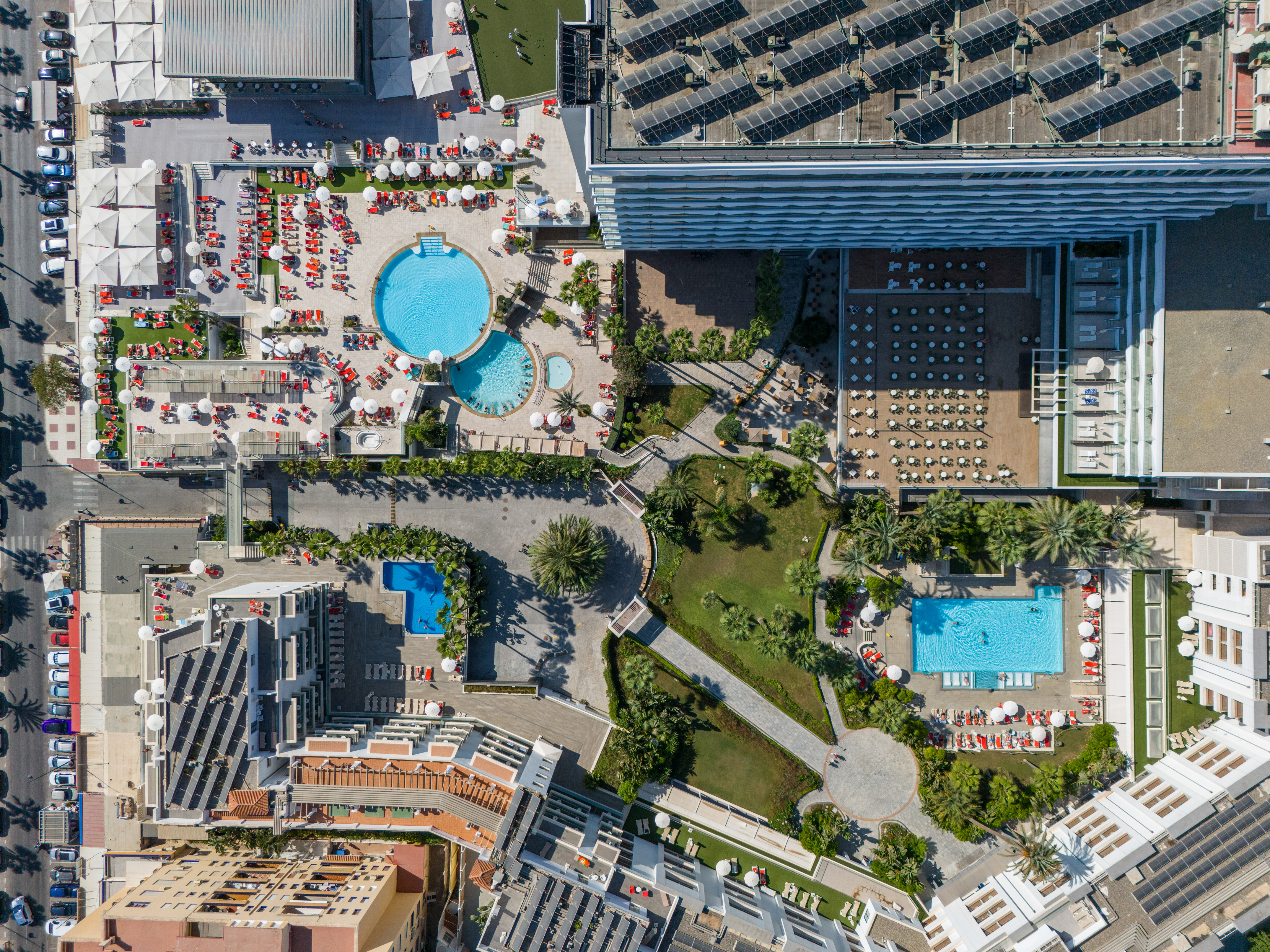 Aerial view of a hotel resort featuring pools, solar panels, and palm trees.