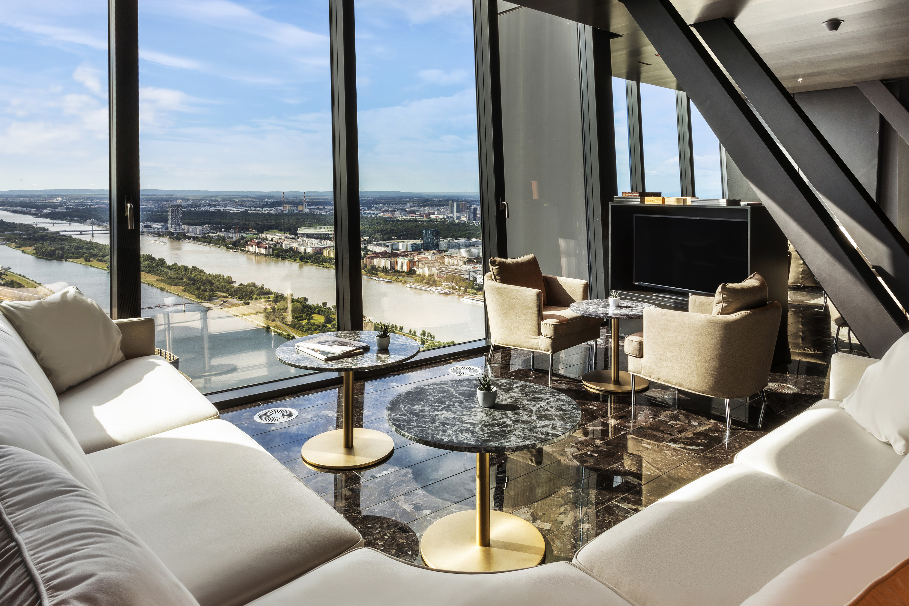 Luxury lounge with panoramic river and city skyline view, modern decor.