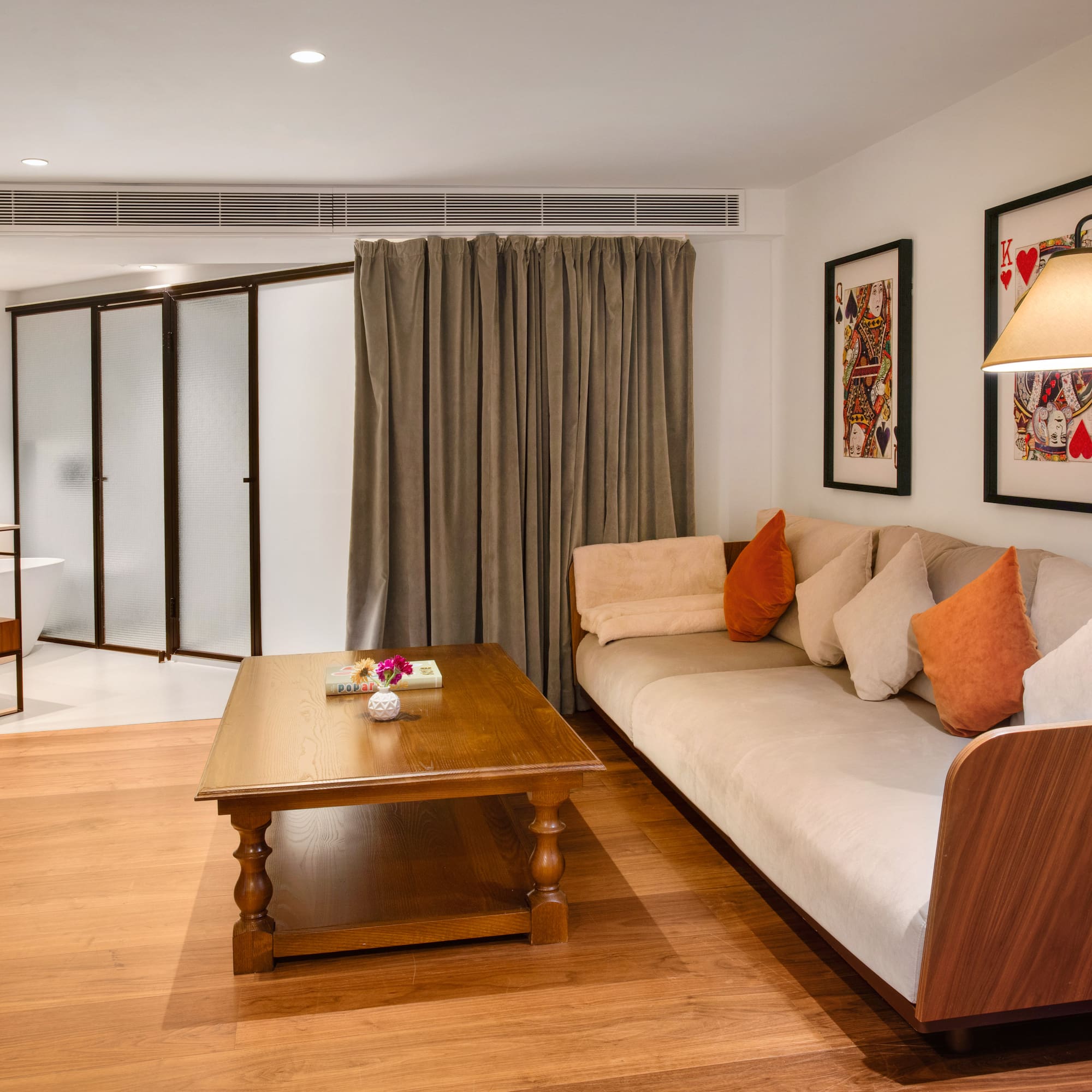 Modern hotel living room with sofa, wooden table, TV, and playing card art.