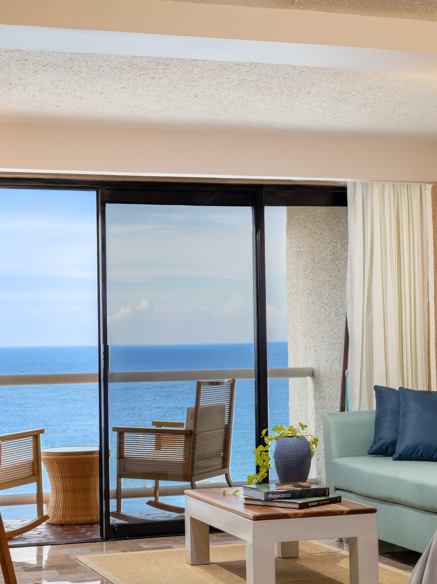 Sala de hotel con balcón y vista al mar.