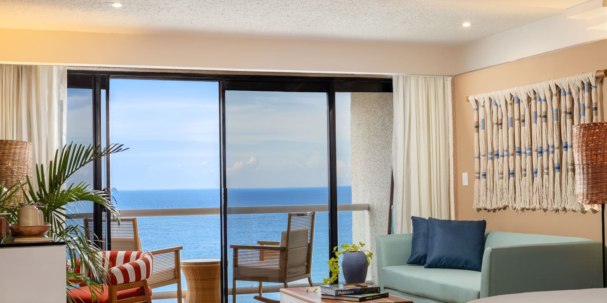 Sala de hotel con balcón y vista al mar.