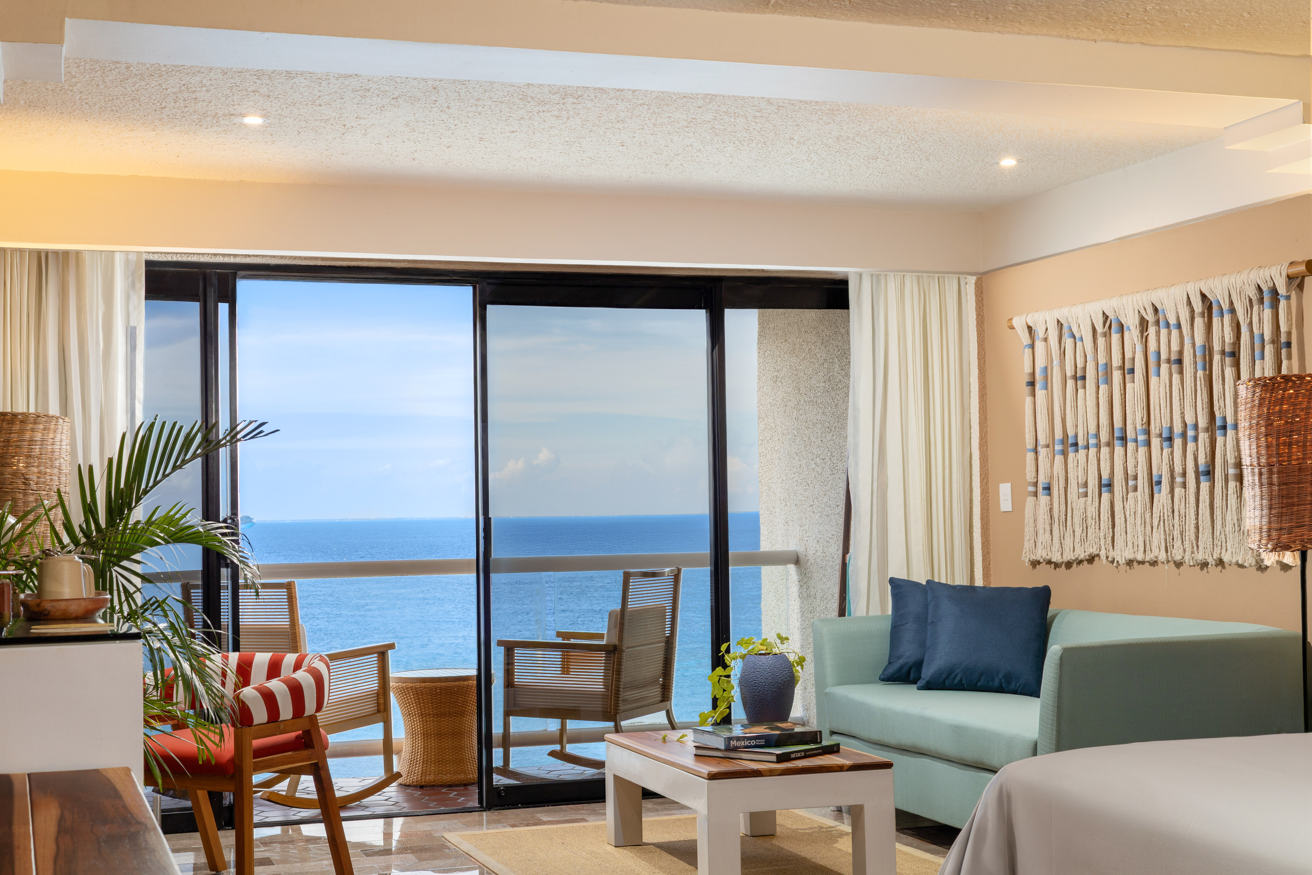 Sala de hotel con balcón y vista al mar.