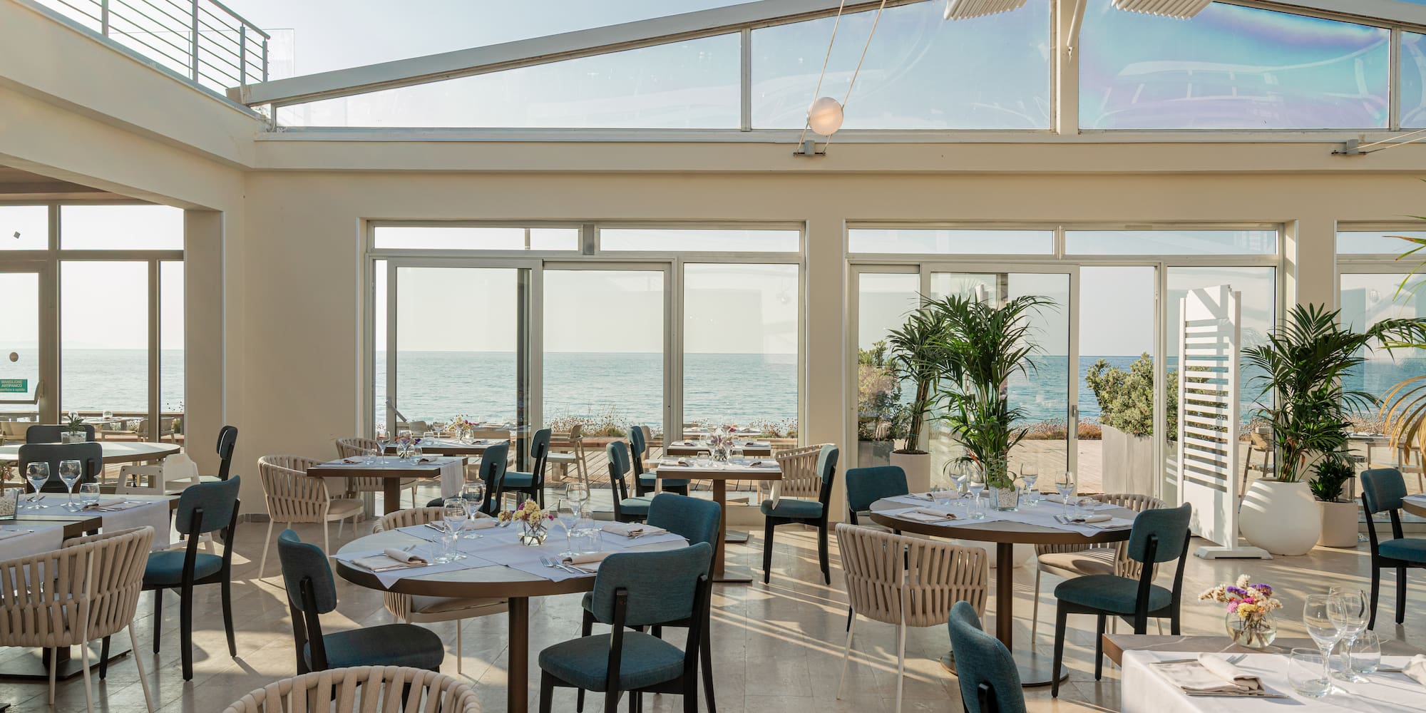 a room with tables and chairs and a view of the ocean
