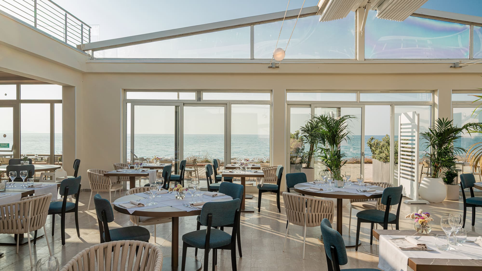 a room with tables and chairs and a view of the ocean