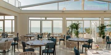 a room with tables and chairs and a view of the ocean
