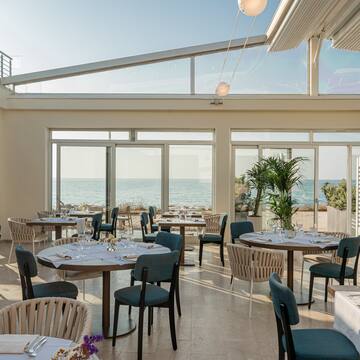 a room with tables and chairs and a view of the ocean