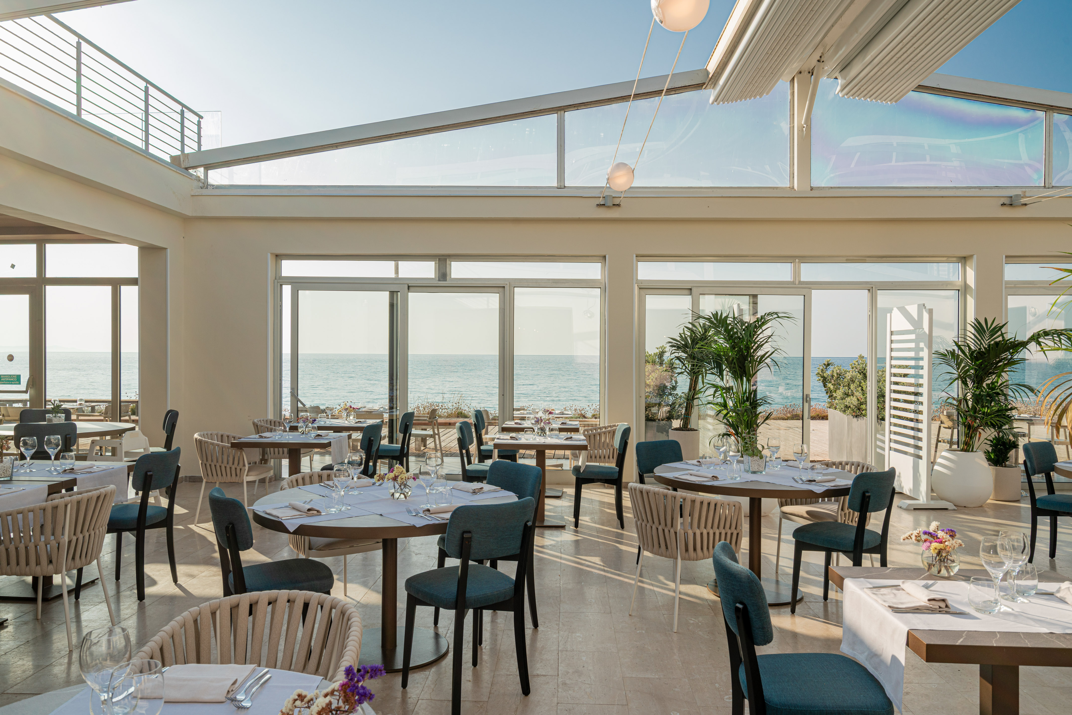 a room with tables and chairs and a view of the ocean