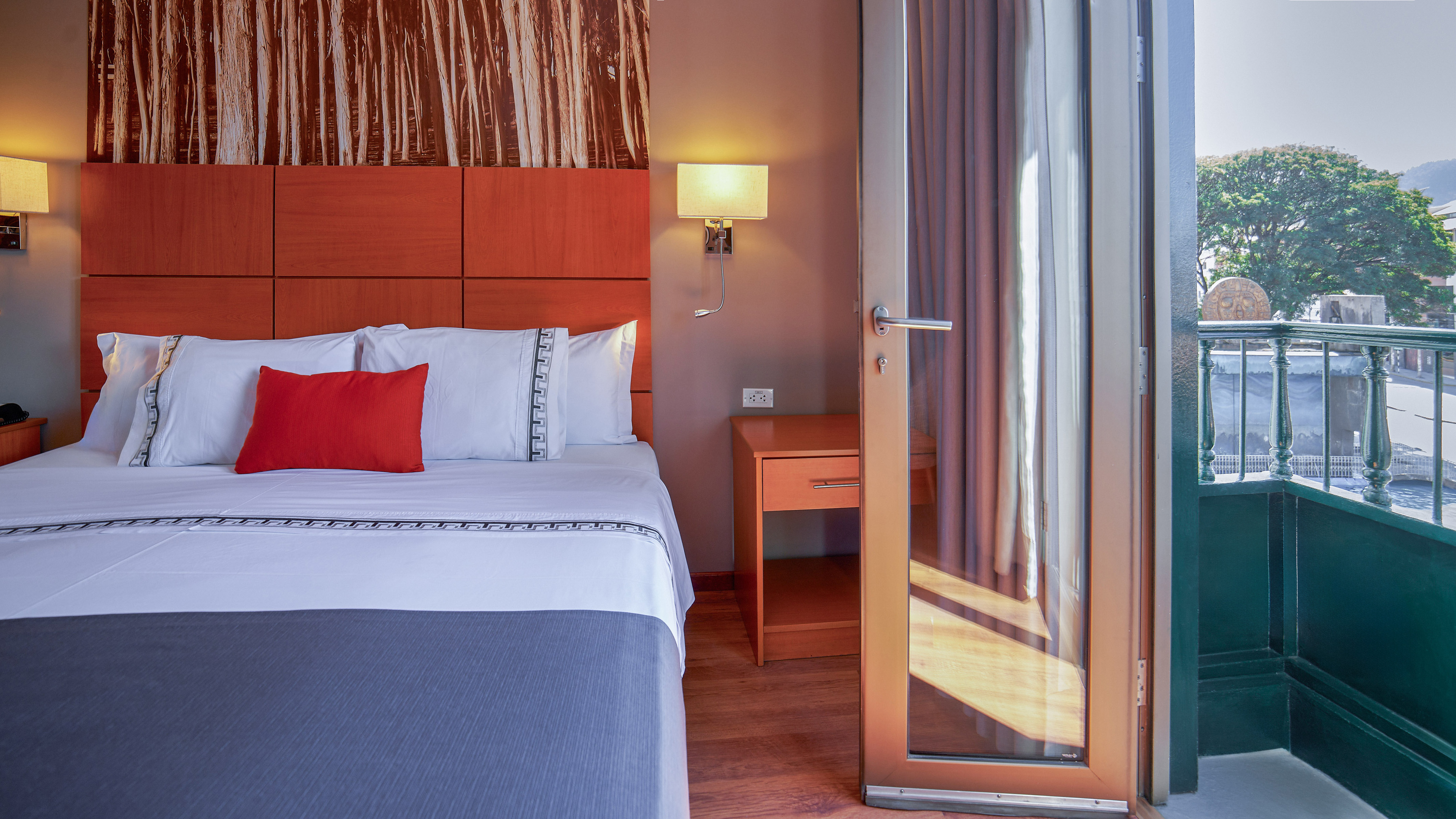 Hotel room with comfortable bed, wooden headboard, and open balcony