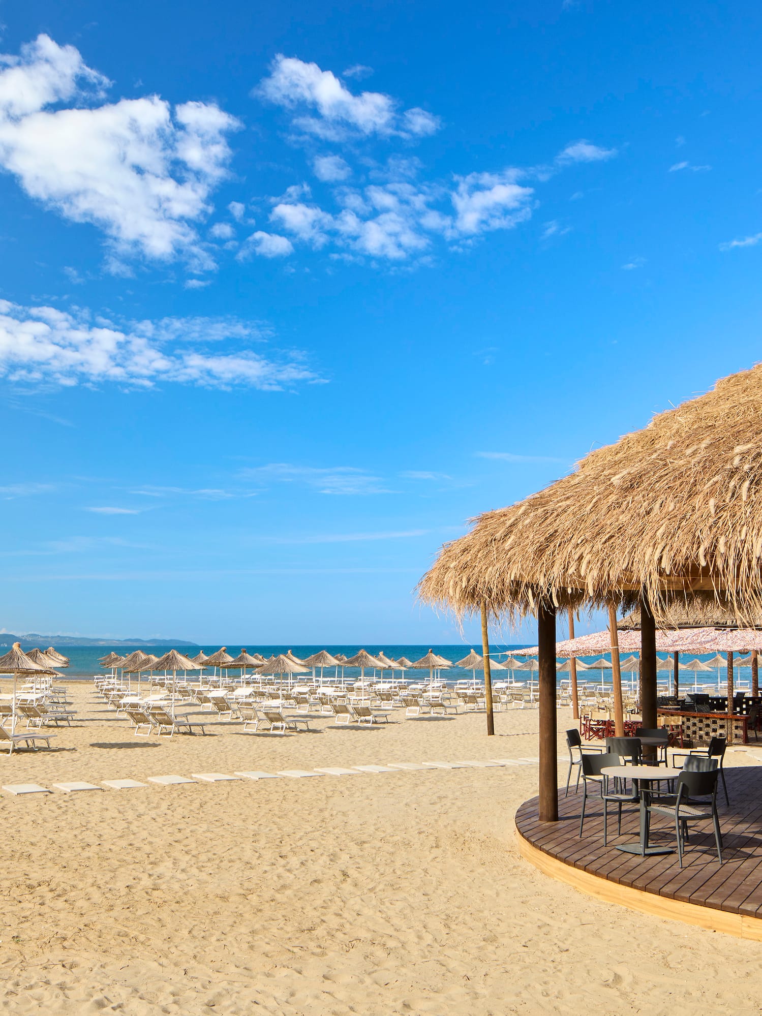 a beach with a thatched roof and chairs