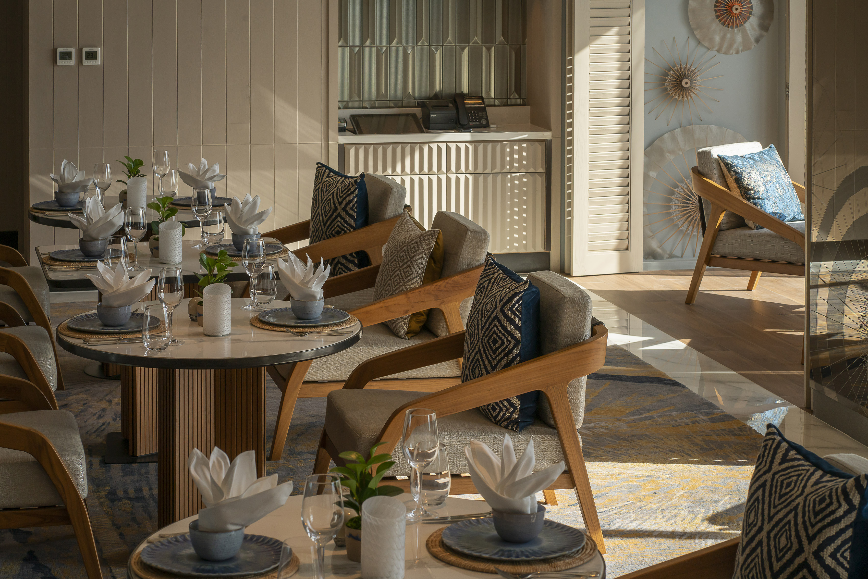 Modern restaurant interior with elegantly set tables and stylish wooden chairs.