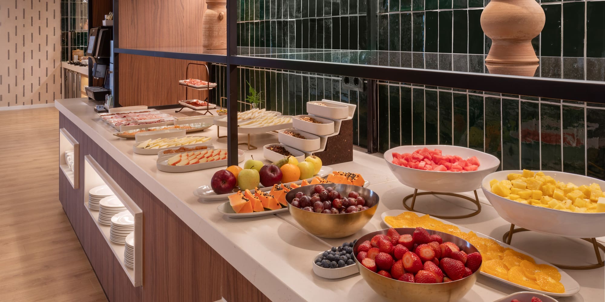 Buffet de desayuno con frutas frescas, embutidos y cereales en un hotel.