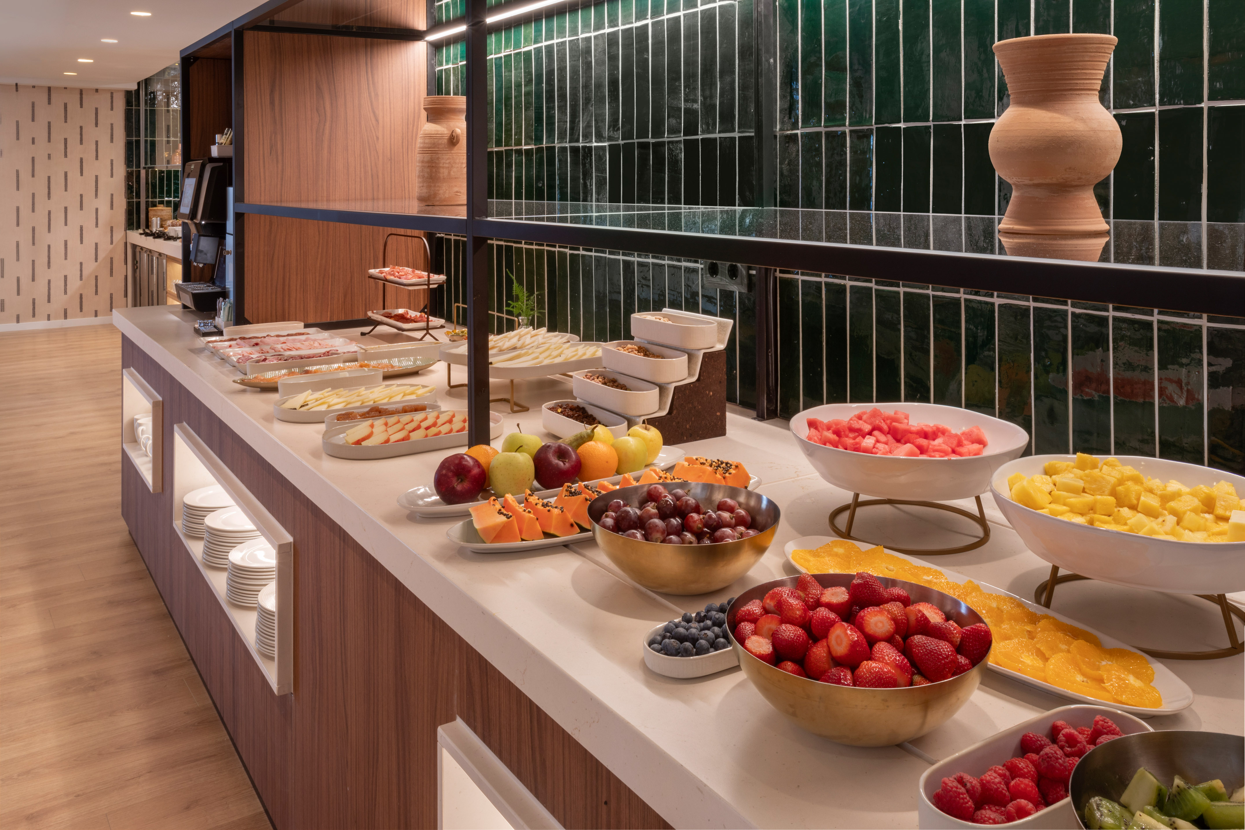 Buffet de desayuno con frutas frescas, embutidos y cereales en un hotel.