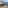 Rustic shacks built on a rocky cliffside next to the dark blue sea.