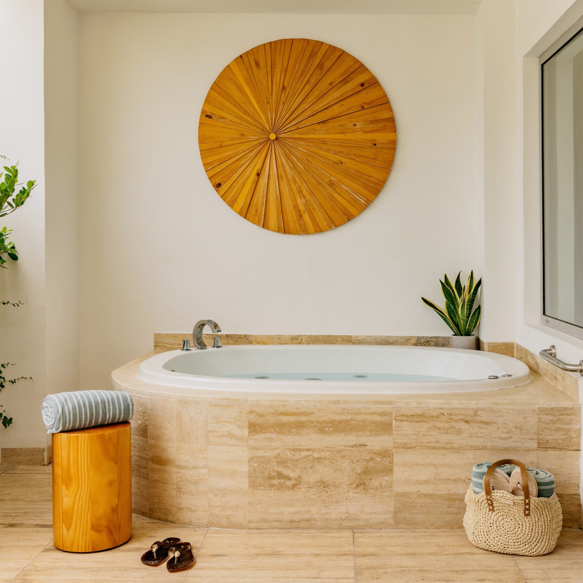 Luxury outdoor jacuzzi on patio with wood wall art, plants, and towels.