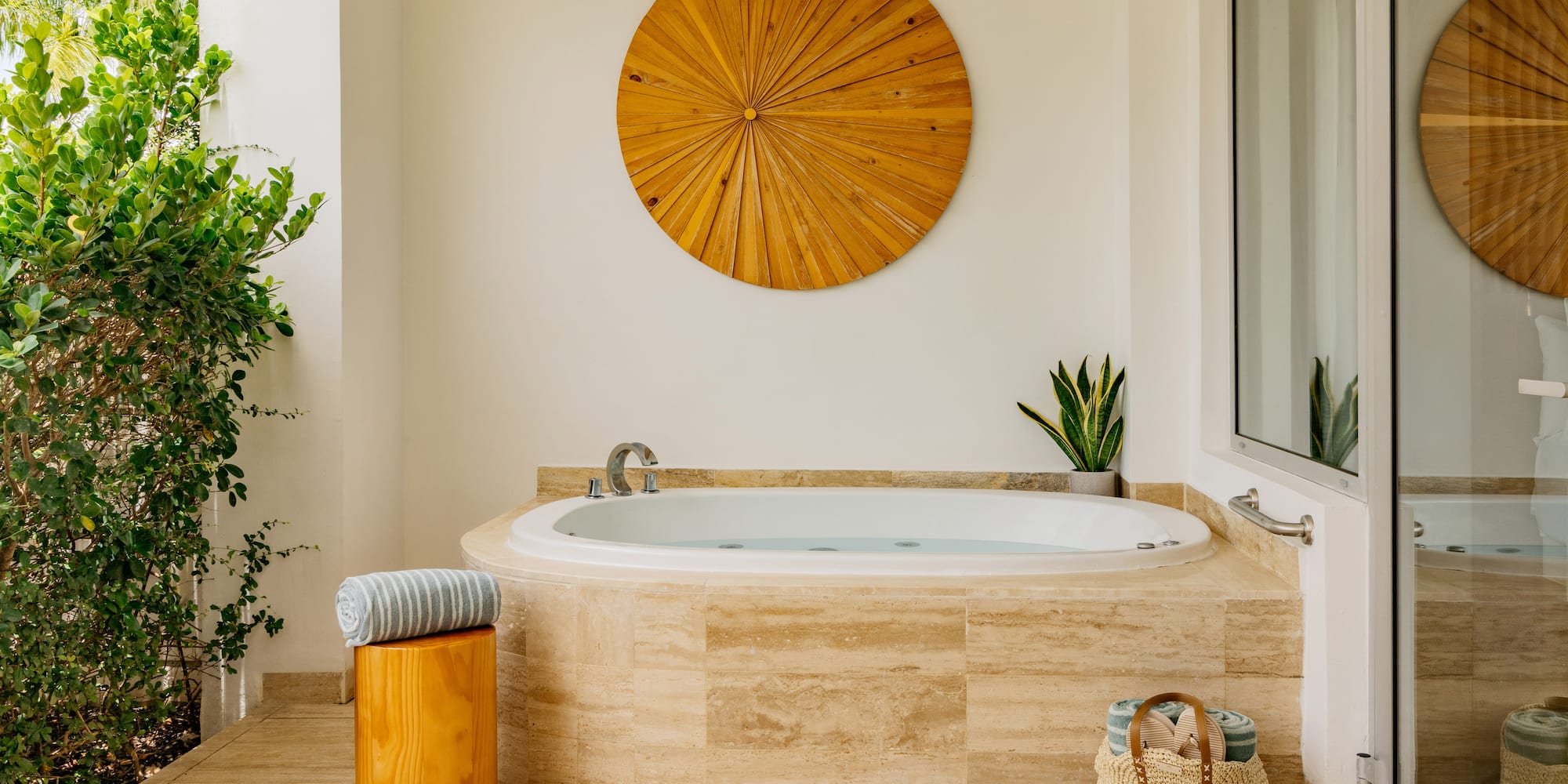 Luxury outdoor jacuzzi on patio with wood wall art, plants, and towels.