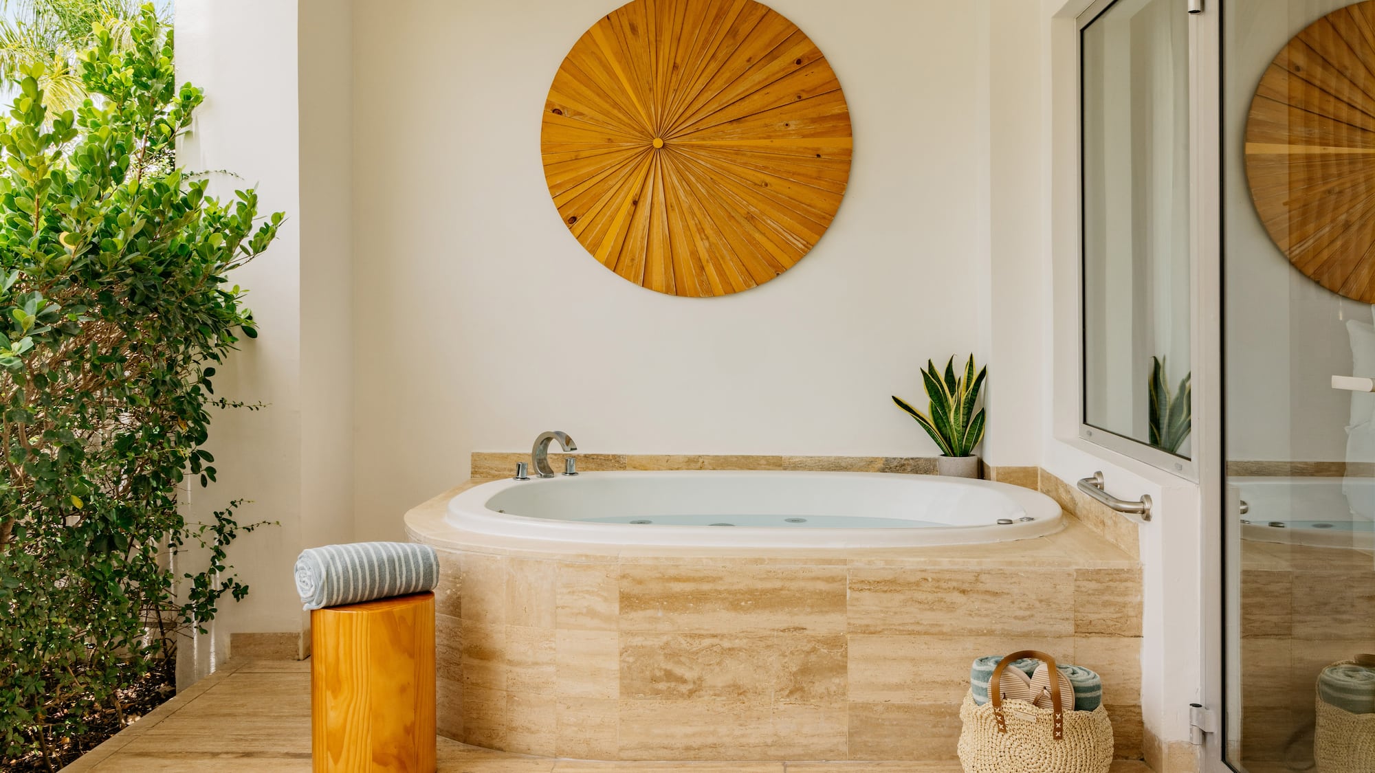 Luxury outdoor jacuzzi on patio with wood wall art, plants, and towels.