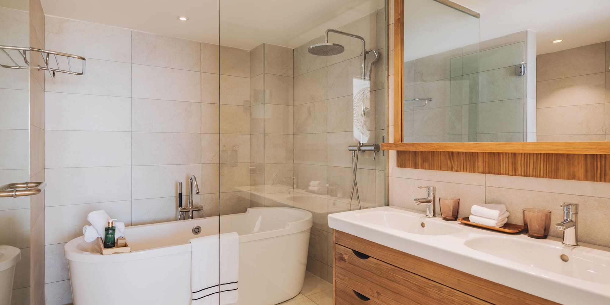 Modern bathroom with freestanding tub, glass shower, and double wood vanity.
