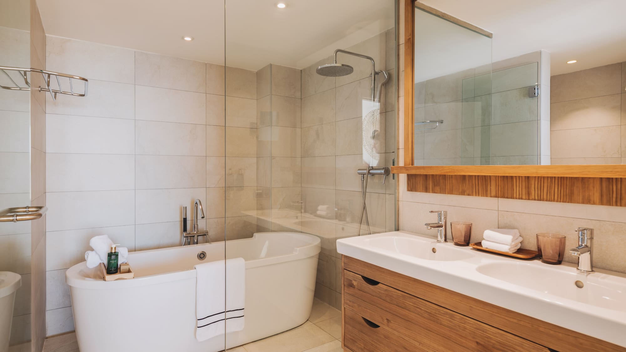 Modern bathroom with freestanding tub, glass shower, and double wood vanity.