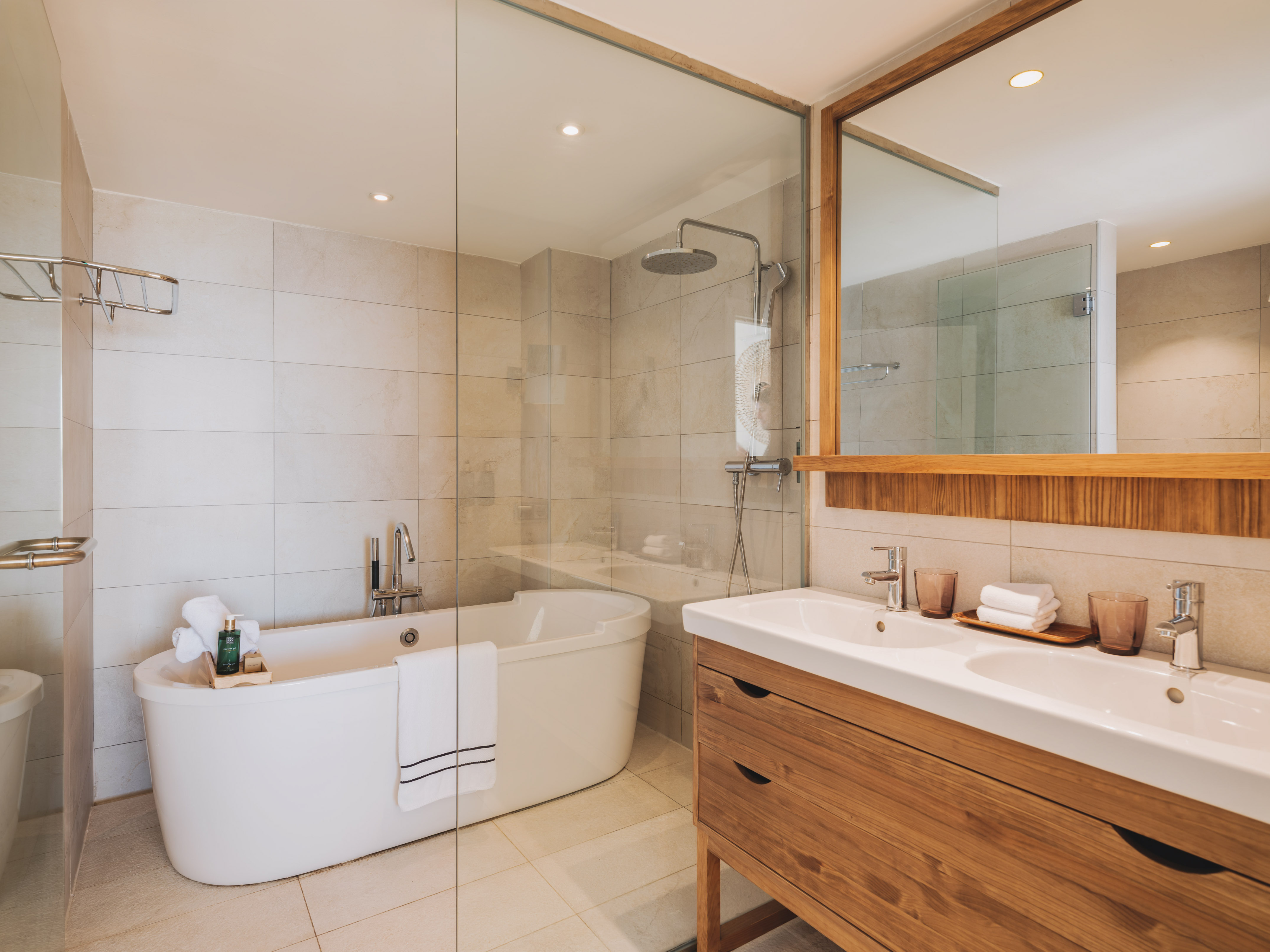 Modern bathroom with freestanding tub, glass shower, and double wood vanity.