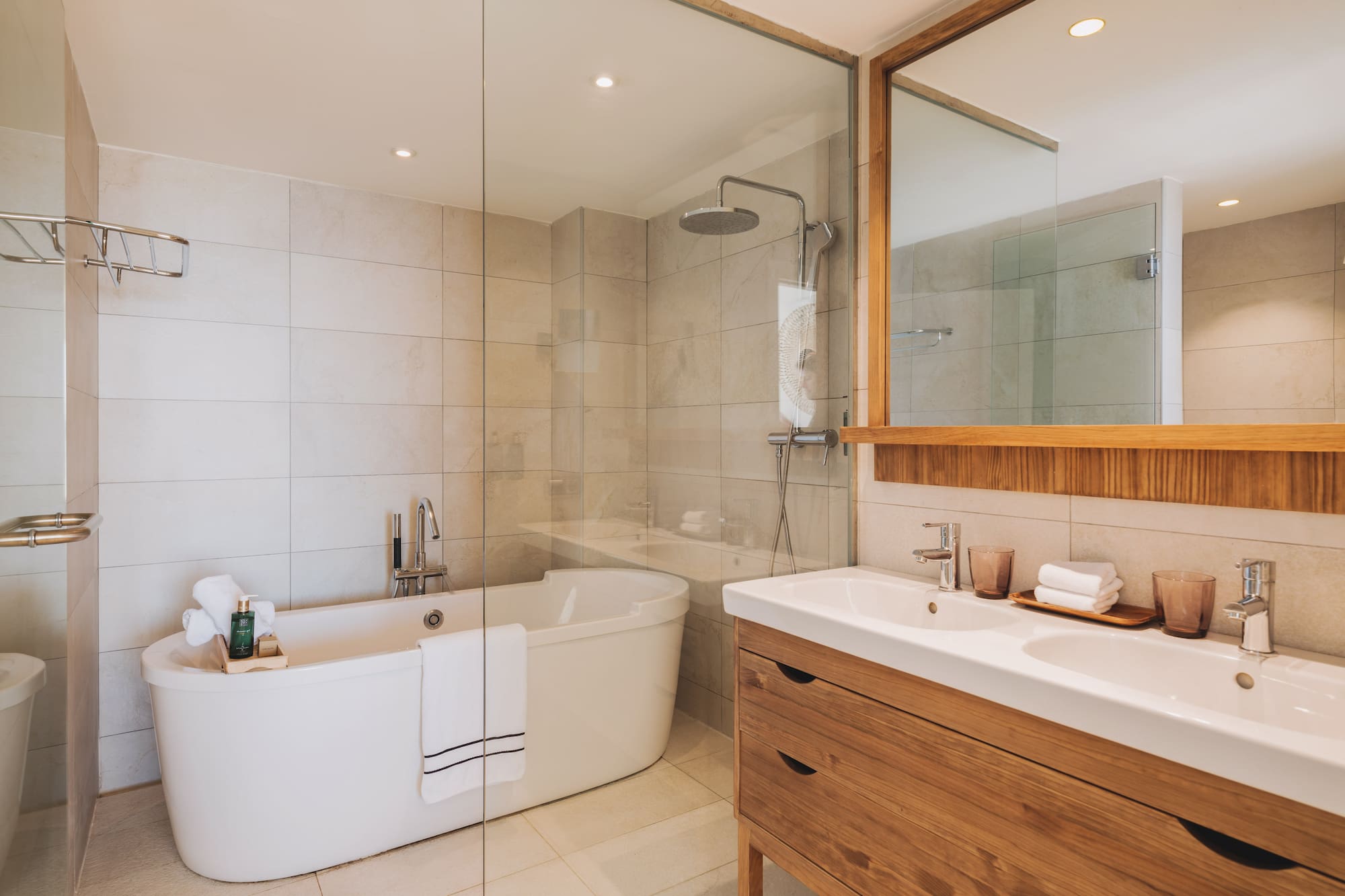 Modern bathroom with freestanding tub, glass shower, and double wood vanity.