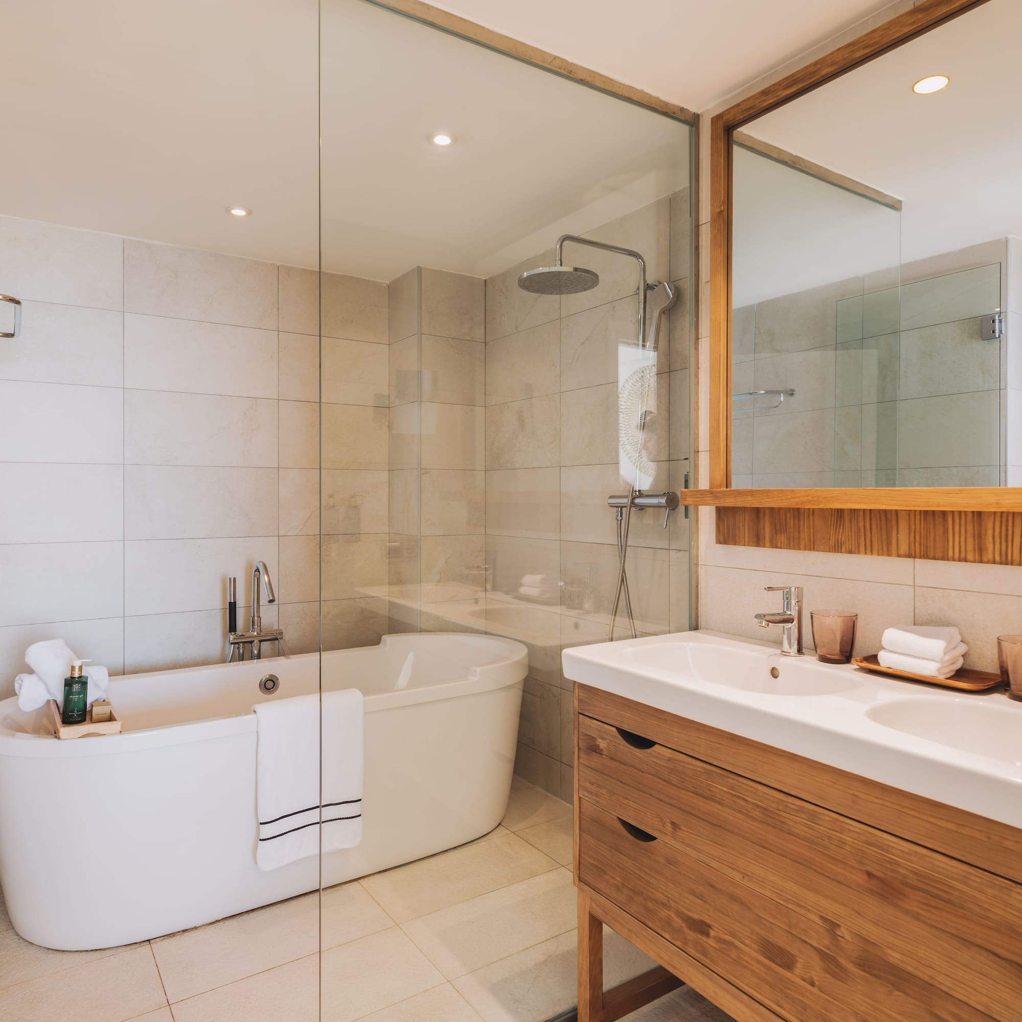 Modern bathroom with freestanding tub, glass shower, and double wood vanity.