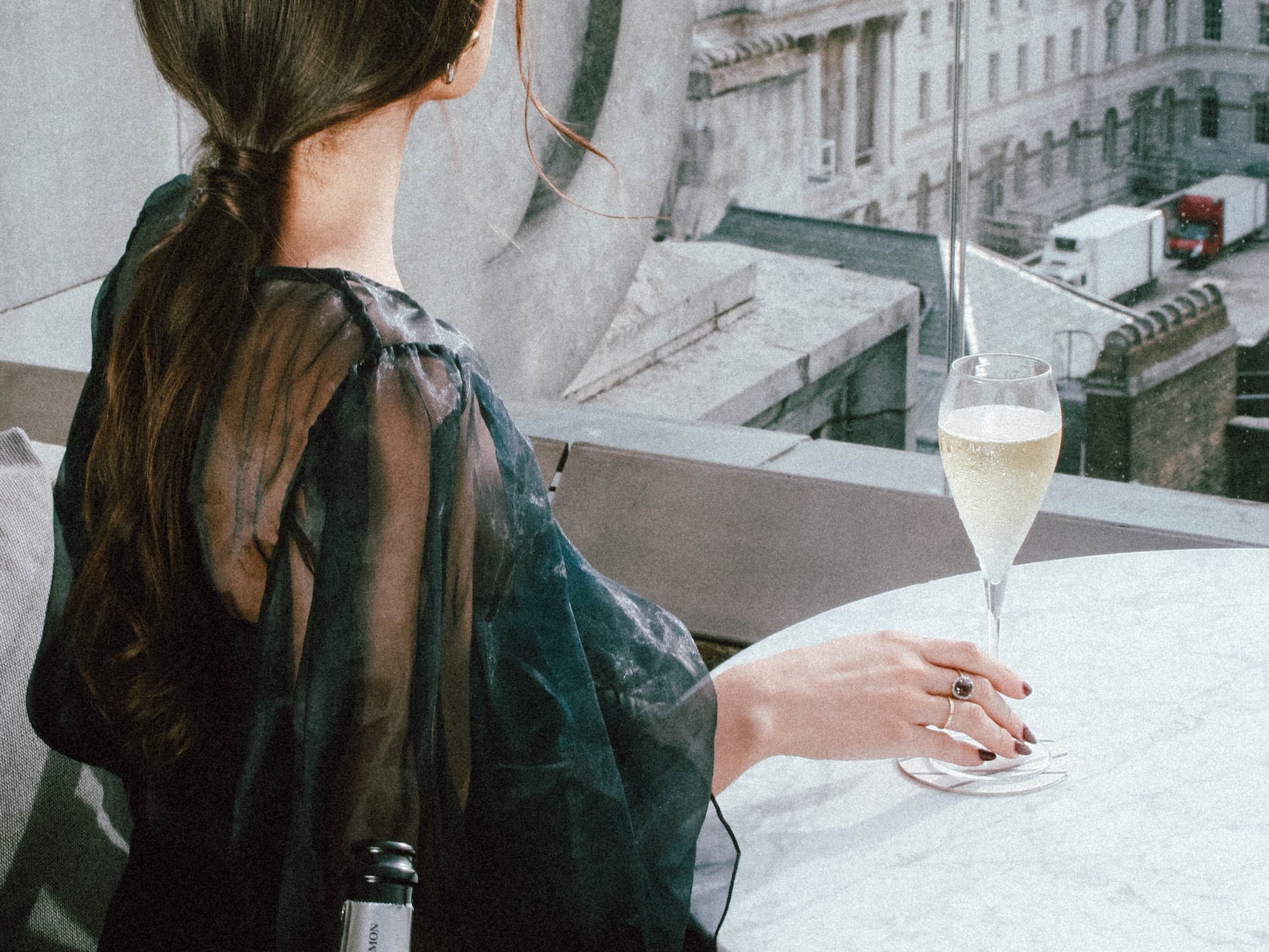 A woman sits at a table with a glass of champagne.