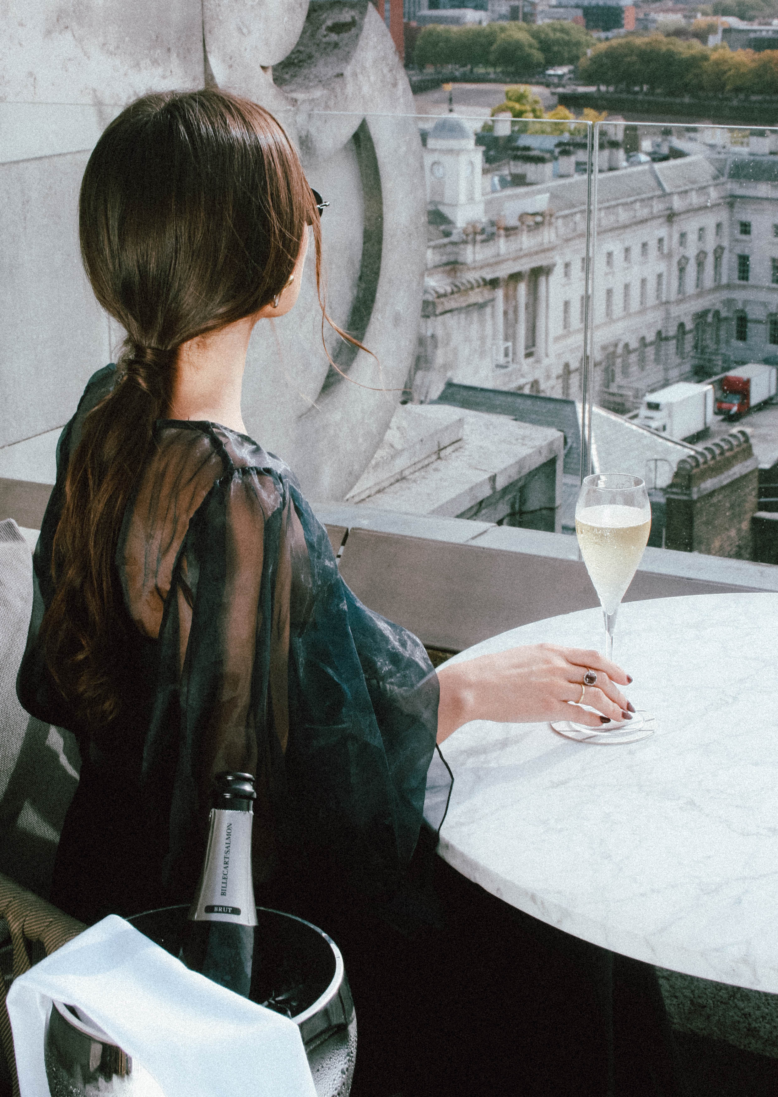 A woman sits at a table with a glass of champagne.