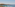 Terrace with sun loungers, umbrellas, overlooking calm bay, sailboat, island.