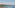 Terrace with sun loungers, umbrellas, overlooking calm bay, sailboat, island.