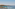 Terrace with sun loungers, umbrellas, overlooking calm bay, sailboat, island.