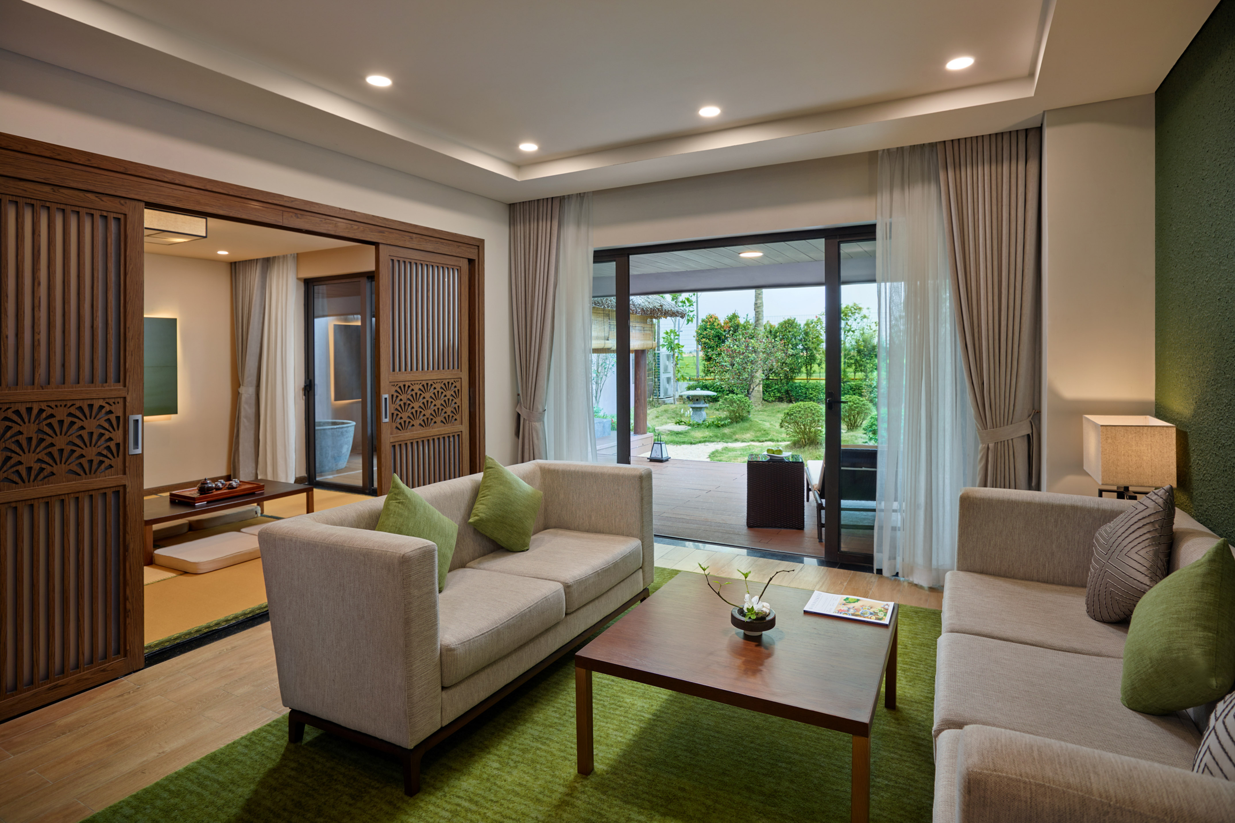 Modern living room with garden view, green rug, and Japanese sliding doors.