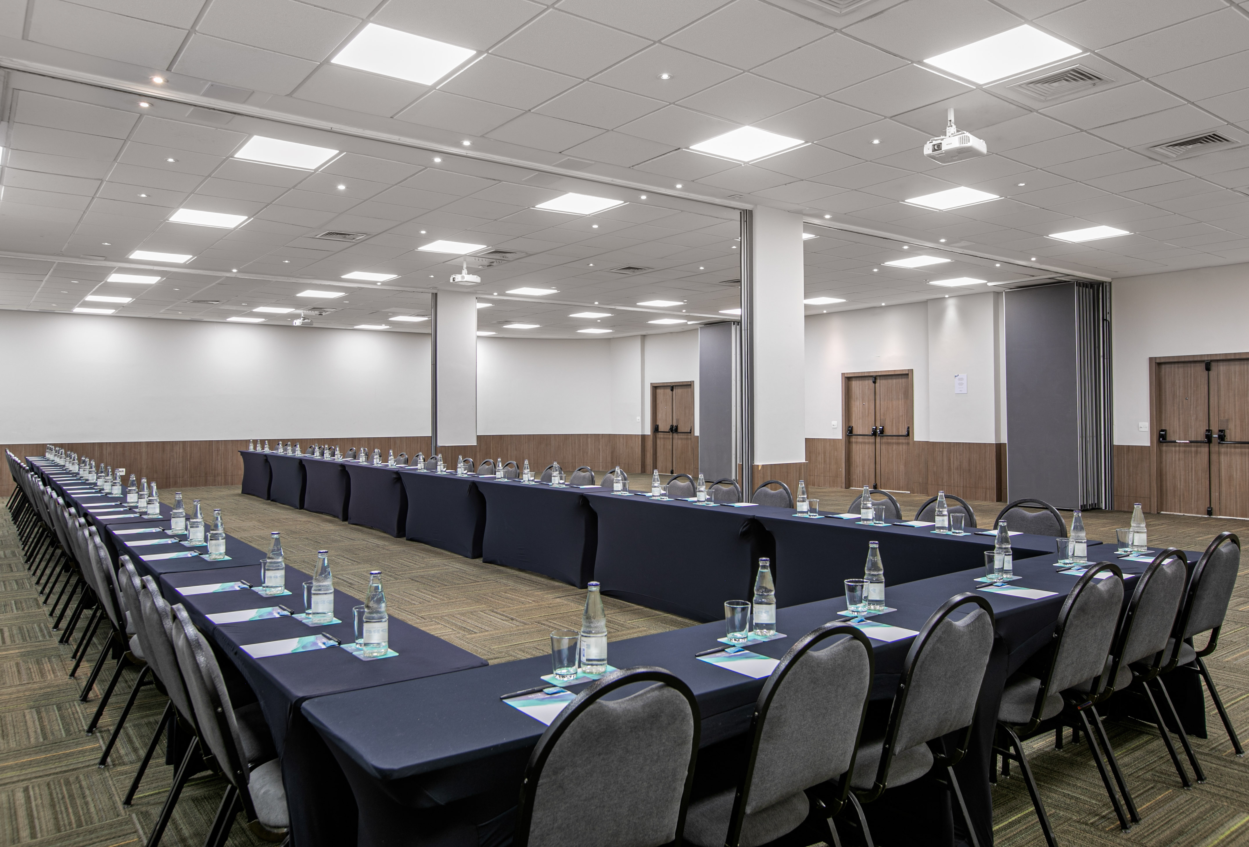 Modern U-shape conference room setup with projector and amenities.