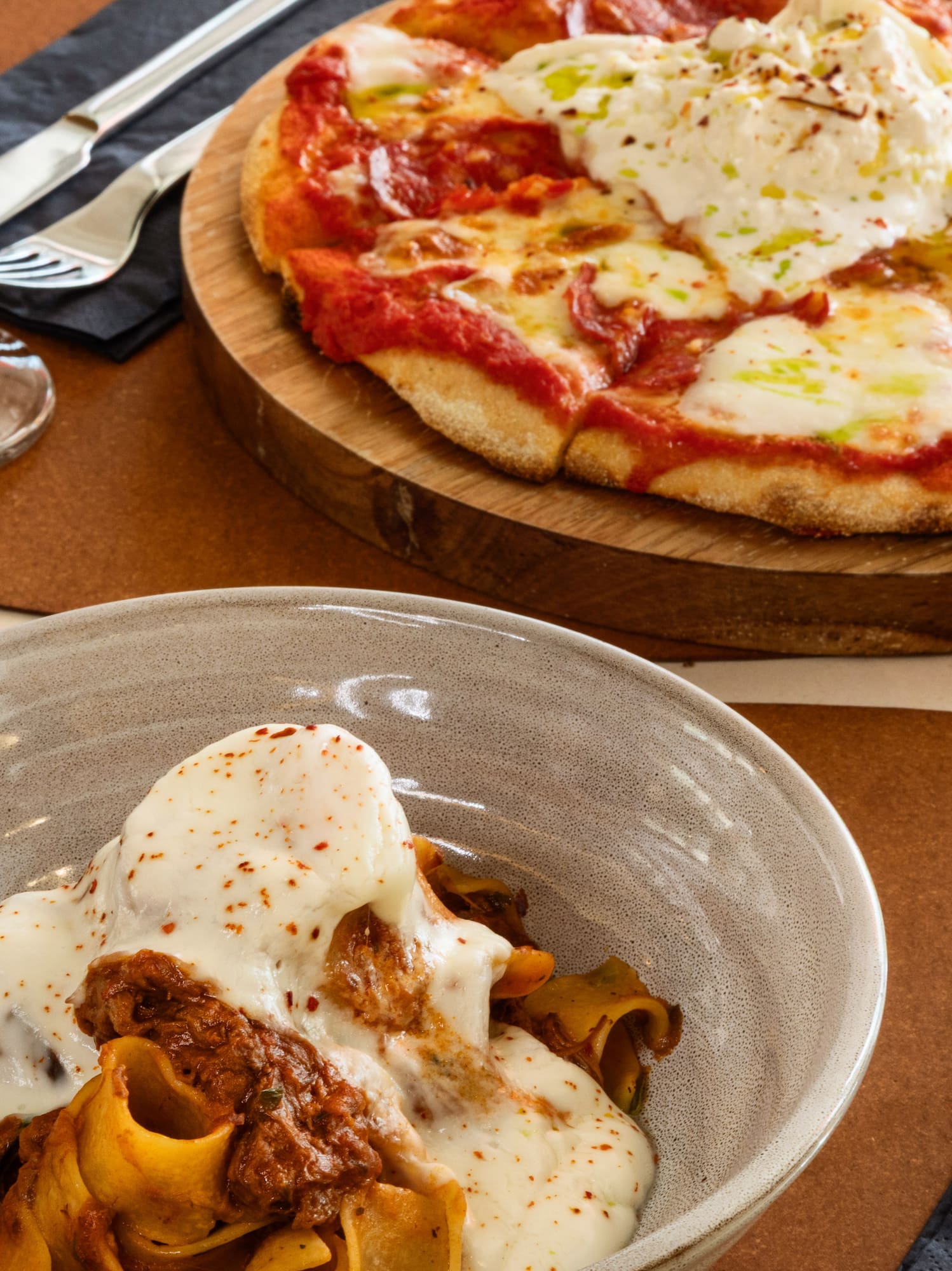 Italian dinner with pasta, burrata pizza, and red wine.