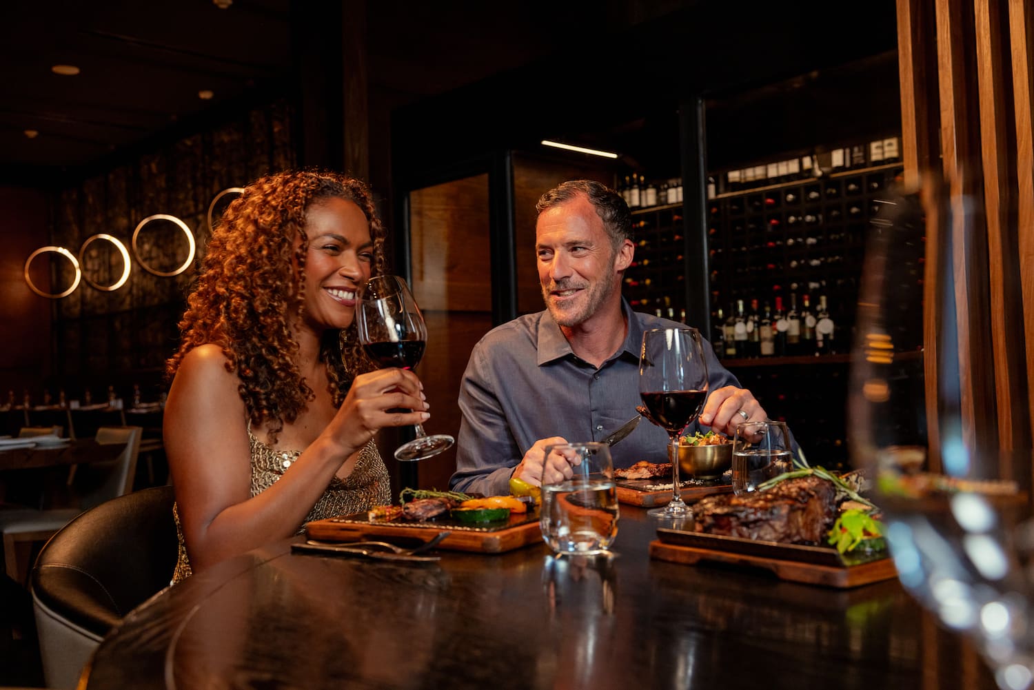 a man and woman sitting at a table with food and drinks