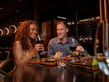 a man and woman sitting at a table with food and drinks